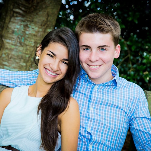 Two smiling person sitting outdoors on a bench