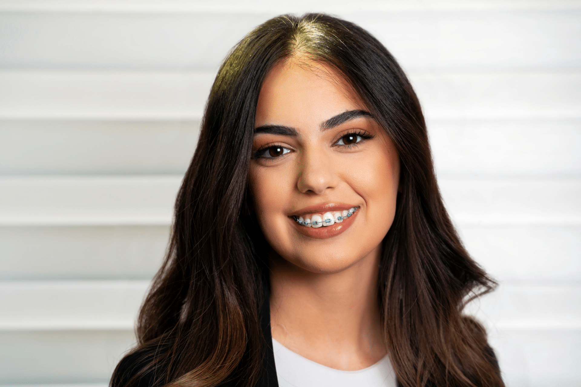 Portrait of a smiling young woman with long dark hair and dental braces